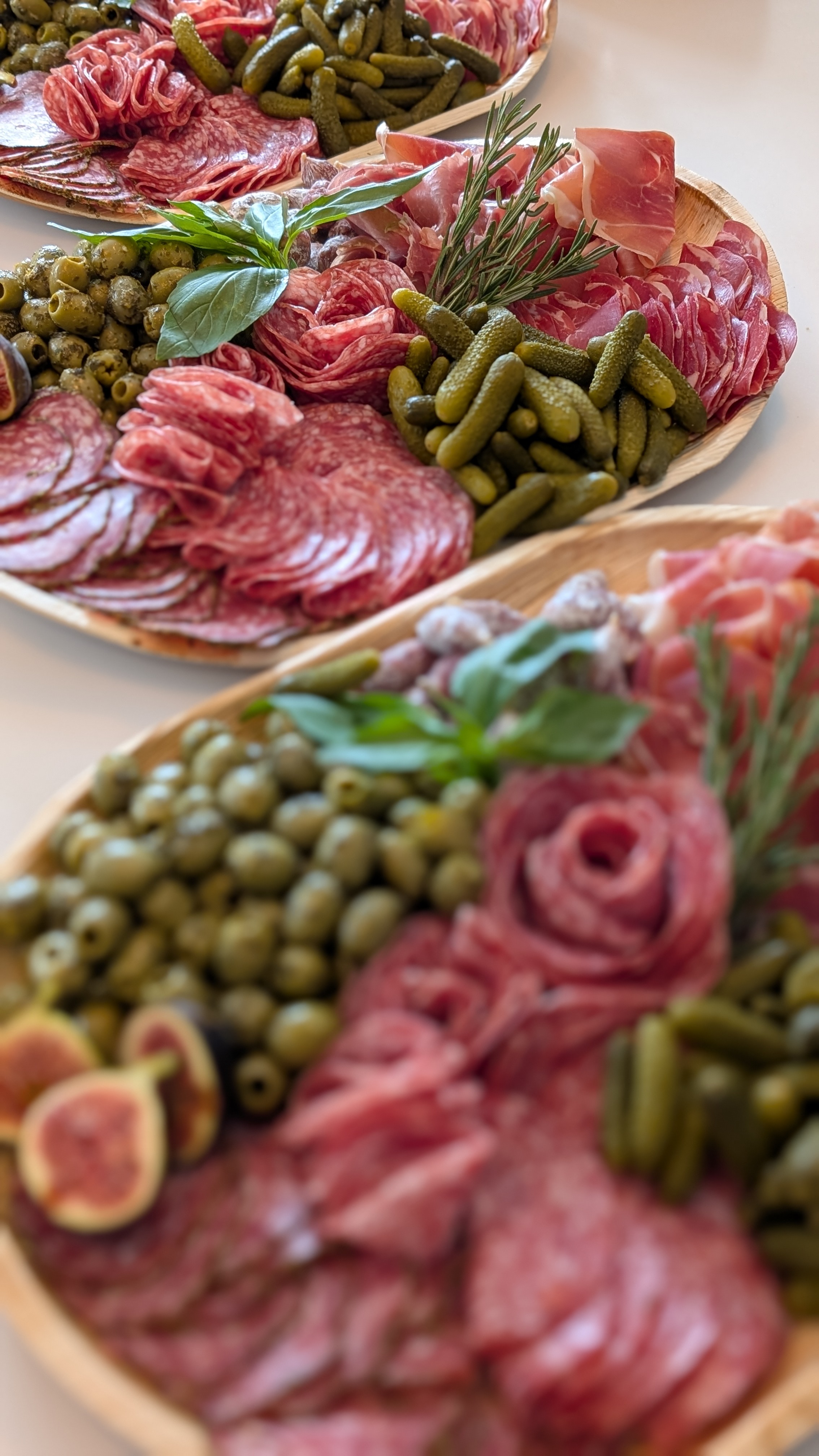 Three salami and charcuterie platters with olives, gherkins and figs